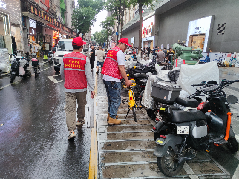 圖：“紅棉老兵”志愿者搬動隨意停放的共享單車.jpg